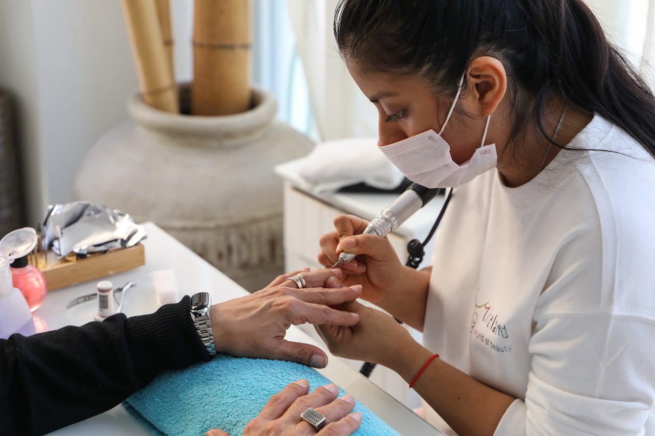 Nail technician performing a manicure with precision and care in a salon setting.