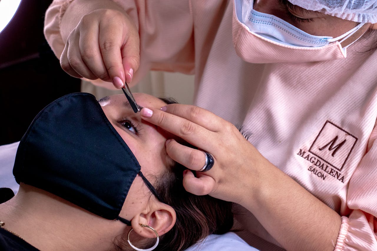 Close-up of an esthetician grooming eyebrows in a beauty salon setting, enhancing facial aesthetics.
